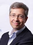 A person wearing glasses and a suitDescription automatically generated with medium confidence